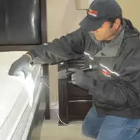 Bed bug inspection technician checking a mattress and bed frame for signs of infestation in Denver, CO