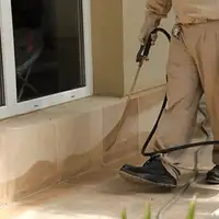 General pest control technician spraying exterior perimeter around a home in Denver, CO