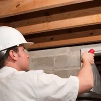 Termite inspection technician checking a basement wall and framing for termite activity in Denver, CO